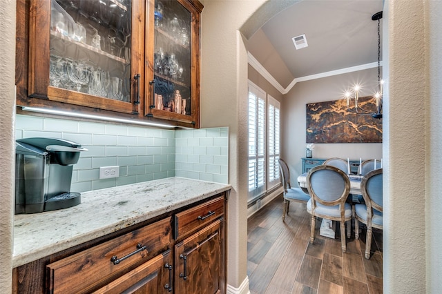 bar featuring visible vents, ornamental molding, dark wood finished floors, arched walkways, and decorative backsplash