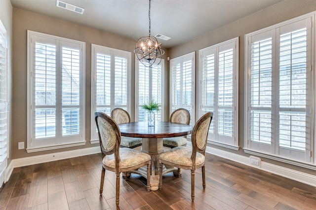 dining space with dark wood finished floors, a notable chandelier, baseboards, and visible vents