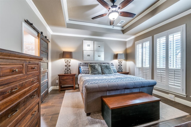 bedroom with wood finish floors, a barn door, baseboards, crown molding, and a raised ceiling