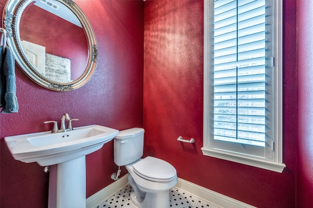 bathroom with tile patterned flooring, baseboards, toilet, a textured wall, and a sink