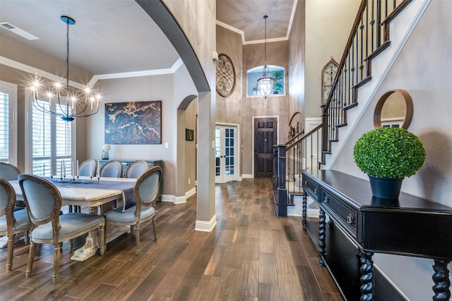 entryway featuring an inviting chandelier, stairway, dark wood-style floors, and arched walkways