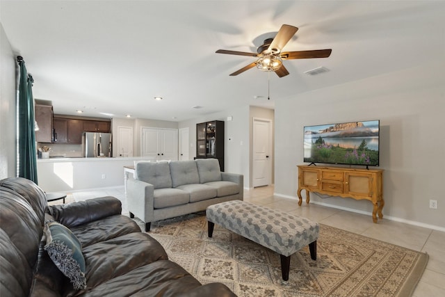 living area featuring light tile patterned floors, ceiling fan, visible vents, and baseboards