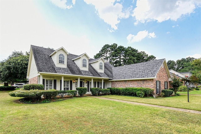 new england style home with brick siding, a front lawn, and roof with shingles