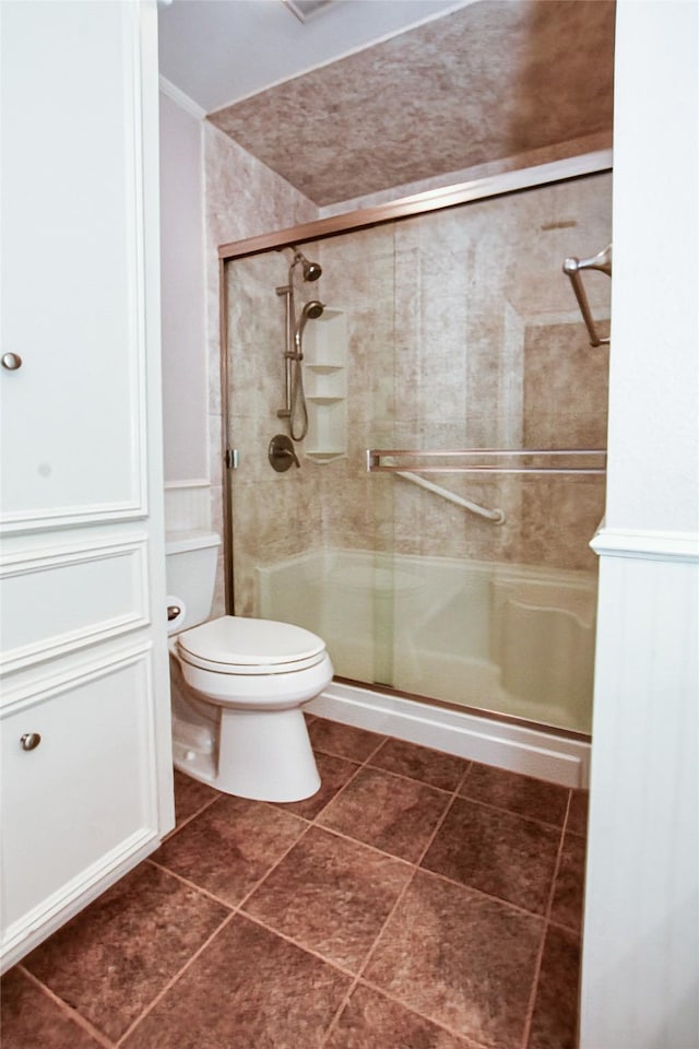 bathroom with toilet, a shower stall, and tile patterned floors