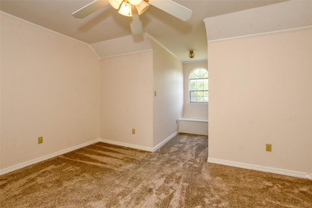 carpeted spare room featuring vaulted ceiling, crown molding, a ceiling fan, and baseboards