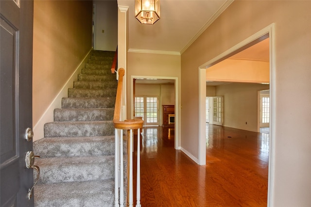 staircase with a wealth of natural light, crown molding, and wood finished floors