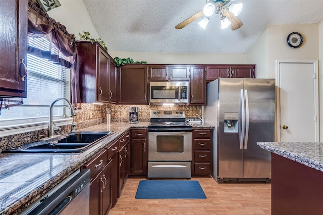 kitchen with stainless steel appliances, light wood-style flooring, dark brown cabinetry, a sink, and a textured ceiling