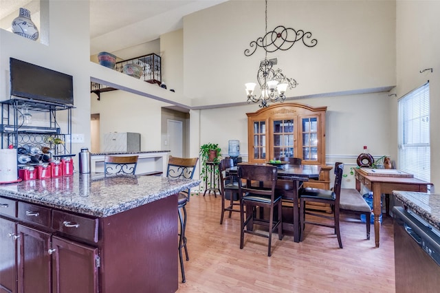 dining area featuring light wood-type flooring, a notable chandelier, and a towering ceiling