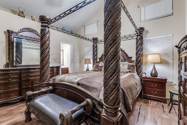 bedroom featuring ensuite bathroom, high vaulted ceiling, and wood finished floors