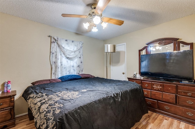 bedroom featuring light wood-style floors, a textured ceiling, and a ceiling fan