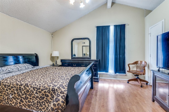 bedroom with vaulted ceiling with beams, a textured ceiling, and wood finished floors