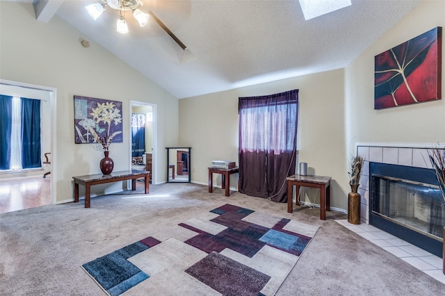 interior space with carpet, a skylight, a tiled fireplace, a ceiling fan, and a textured ceiling