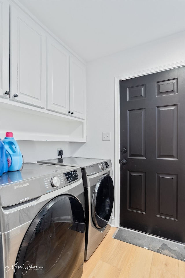 laundry area featuring wood finished floors, cabinet space, and separate washer and dryer