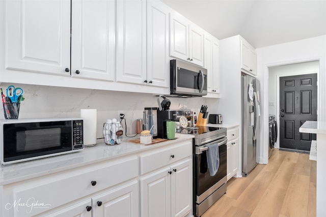 kitchen featuring washer / clothes dryer, light countertops, light wood-style flooring, appliances with stainless steel finishes, and white cabinetry