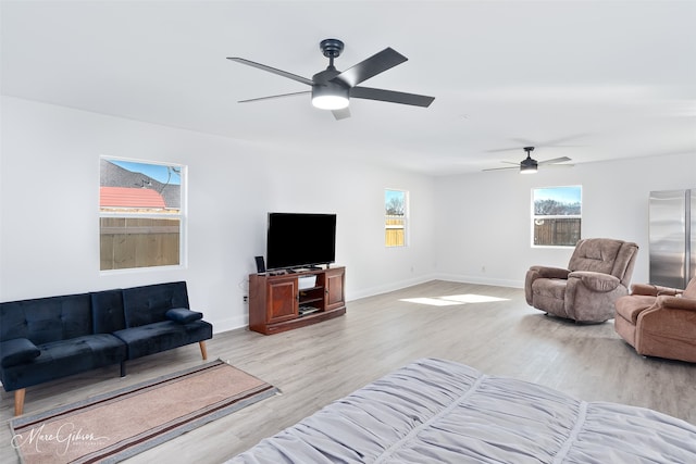 living room featuring light wood-style floors, a healthy amount of sunlight, and baseboards