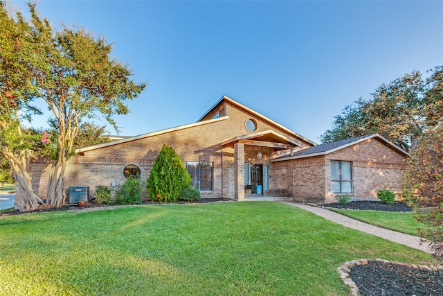 view of front of home featuring brick siding, a front lawn, and cooling unit