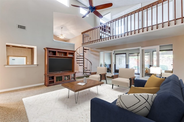 carpeted living room with baseboards, visible vents, a ceiling fan, a high ceiling, and stairs