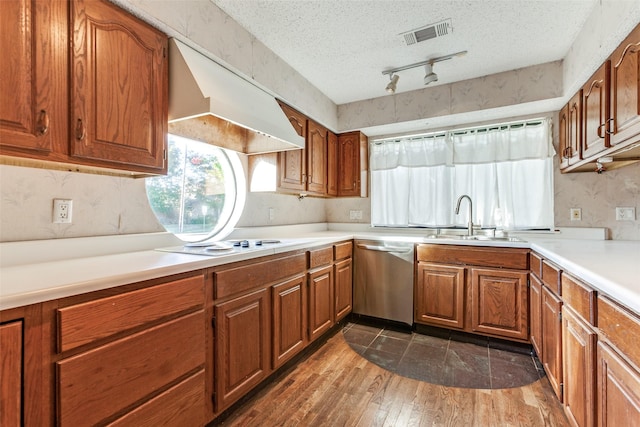 kitchen with a textured ceiling, under cabinet range hood, a sink, visible vents, and stainless steel dishwasher