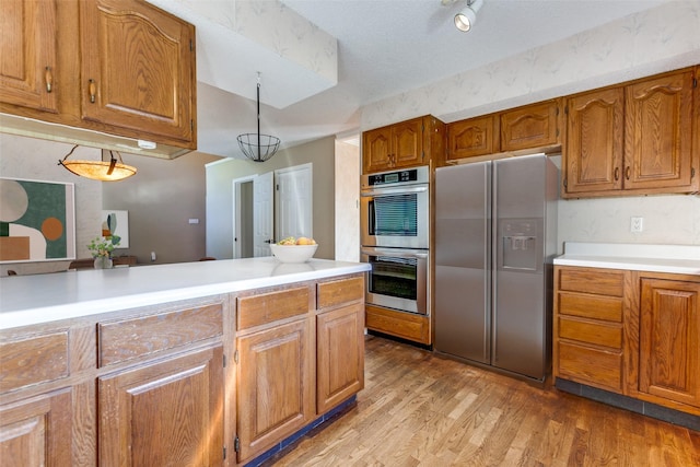 kitchen featuring stainless steel double oven, refrigerator with ice dispenser, light countertops, light wood-type flooring, and brown cabinets