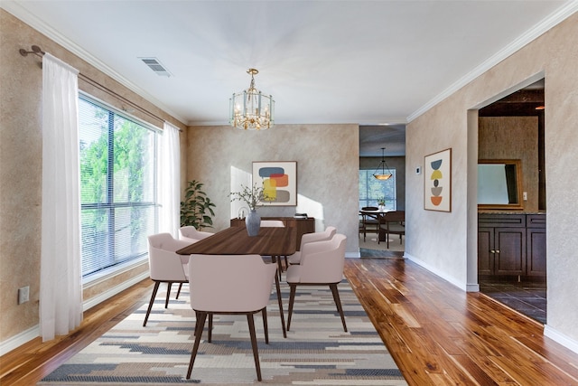 dining room with a chandelier, visible vents, ornamental molding, and wood finished floors