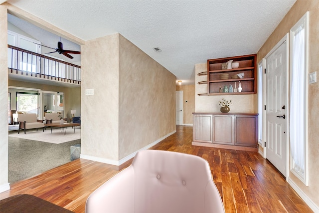 interior space featuring baseboards, a textured ceiling, visible vents, and hardwood / wood-style floors