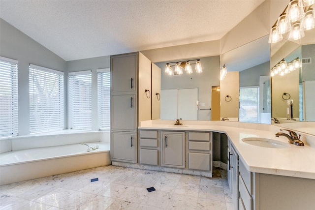 bathroom featuring a garden tub, a textured ceiling, vaulted ceiling, and a sink