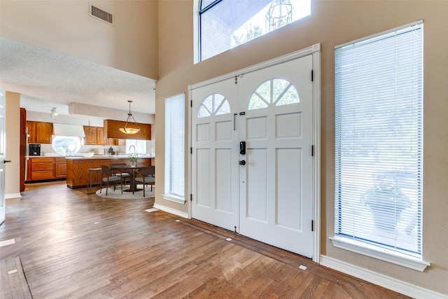 foyer featuring light wood-type flooring, a healthy amount of sunlight, visible vents, and baseboards