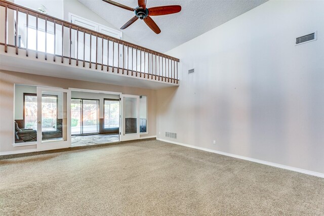 carpeted living area with ceiling fan, visible vents, baseboards, stairway, and a tiled fireplace