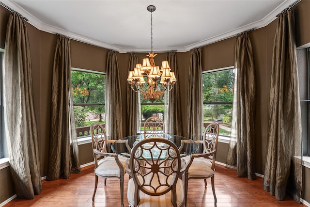 dining area featuring a healthy amount of sunlight, hardwood / wood-style flooring, ornamental molding, and a notable chandelier