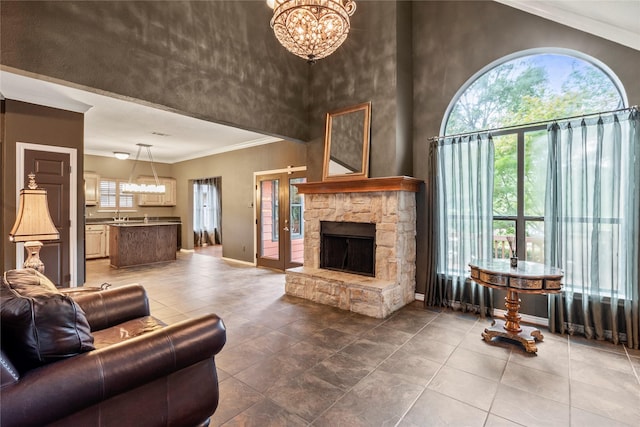 living room featuring a stone fireplace, a high ceiling, a wealth of natural light, and crown molding