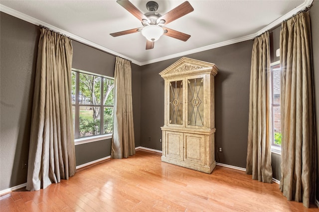 unfurnished room with ornamental molding, light wood-style flooring, and baseboards