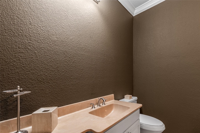 bathroom with crown molding, a textured wall, vanity, and toilet