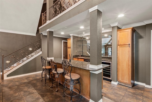 kitchen featuring beverage cooler, a breakfast bar area, dark stone countertops, and baseboards