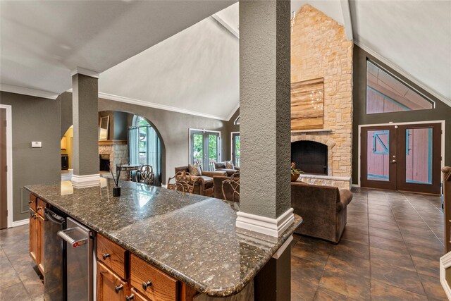 kitchen with a fireplace, open floor plan, french doors, brown cabinets, and dark stone counters