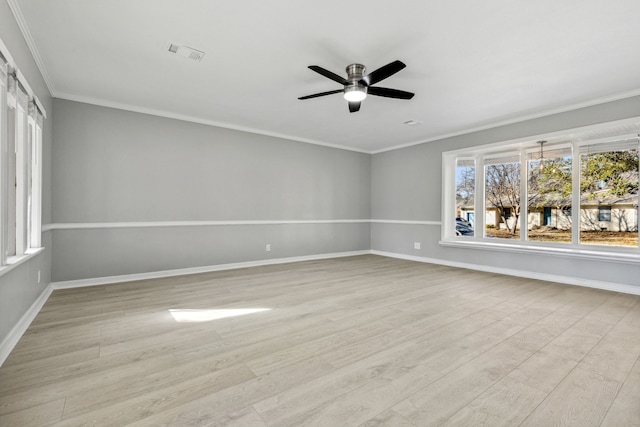 spare room with light wood-type flooring, crown molding, and baseboards