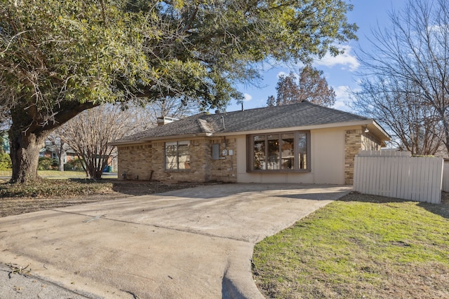 view of front facade featuring a shingled roof, a front yard, fence, and brick siding