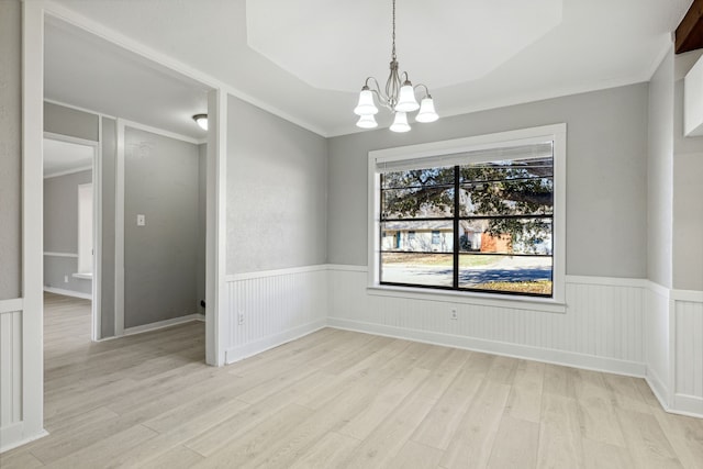 unfurnished dining area featuring a wainscoted wall, light wood-style flooring, and crown molding