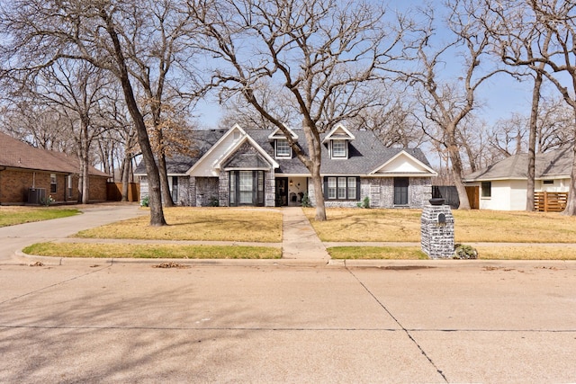 view of front of house featuring central air condition unit, brick siding, fence, roof with shingles, and a front yard