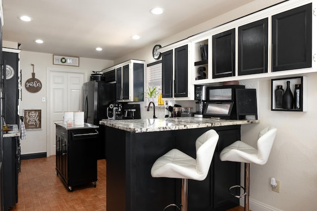 kitchen featuring recessed lighting, freestanding refrigerator, dark cabinetry, a peninsula, and baseboards