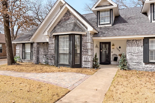 view of front of property with roof with shingles and brick siding