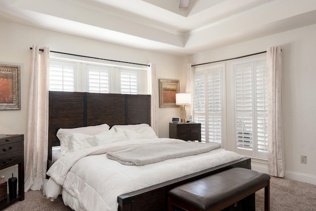 carpeted bedroom featuring a raised ceiling and baseboards