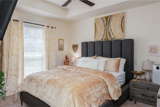 bedroom with ceiling fan and a tray ceiling