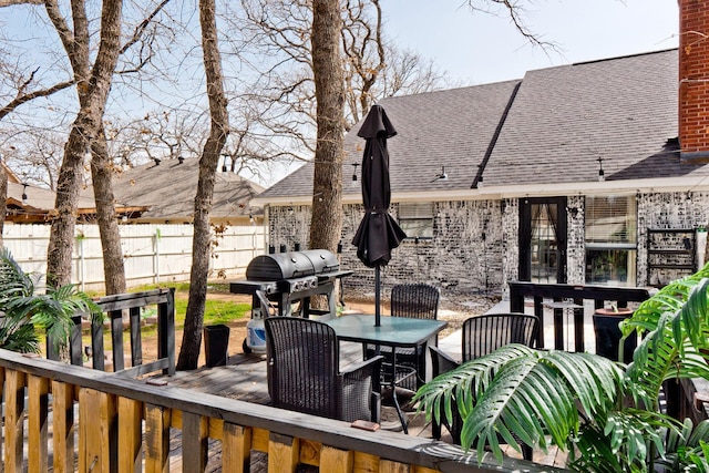 deck with outdoor dining space, a grill, and fence