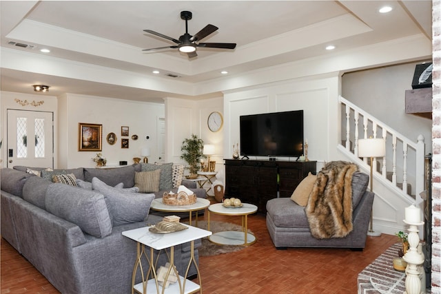 living area with stairs, visible vents, and a raised ceiling