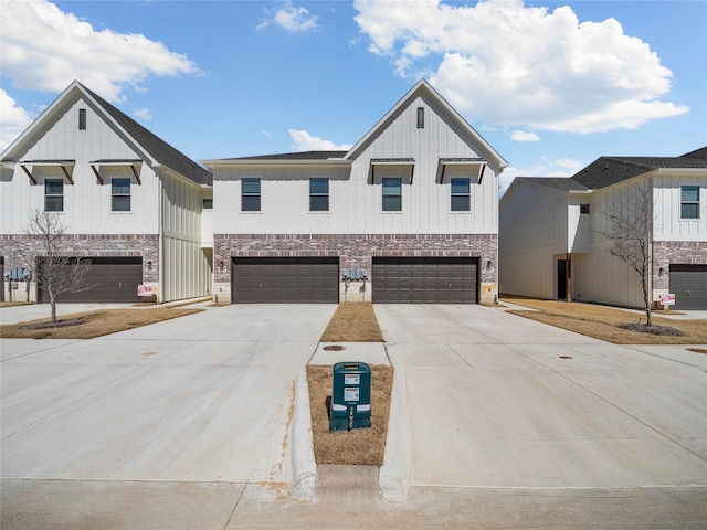 view of front of home with a garage, brick siding, board and batten siding, and concrete driveway