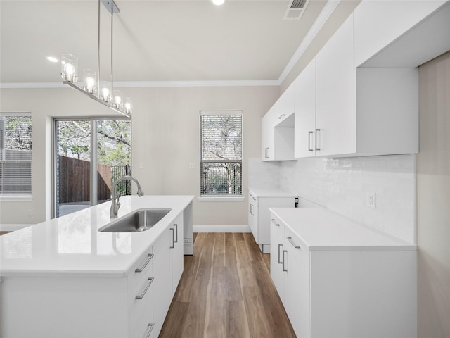 kitchen with light countertops, ornamental molding, a sink, and tasteful backsplash