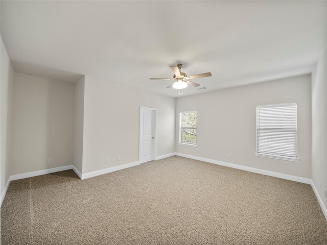 carpeted spare room featuring baseboards, visible vents, and a ceiling fan