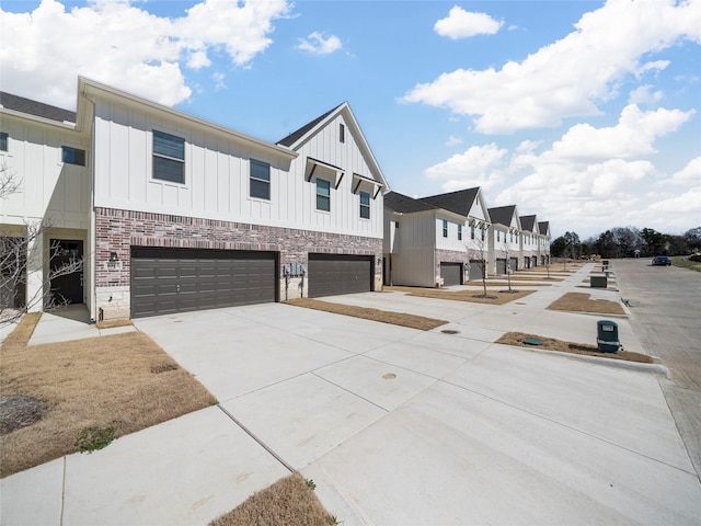 view of front of property featuring board and batten siding, a residential view, driveway, and a garage