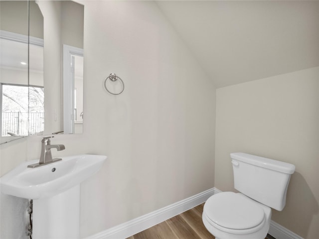 half bath featuring baseboards, a sink, toilet, and wood finished floors