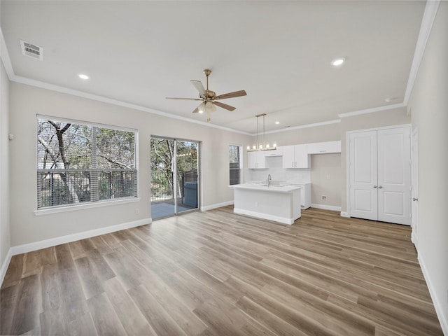 unfurnished living room with baseboards, visible vents, light wood-style flooring, ornamental molding, and ceiling fan with notable chandelier